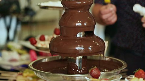 Party and celebration. People dipped strawberries in chocolate fountain. Celebration.