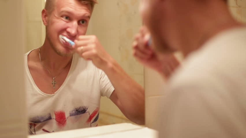 A man brushing his teeth in the bathroom at home