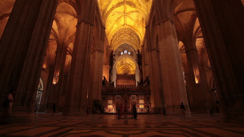 Spectators walk in historic Seville Basilica Cathedral in Seville Spain. Tourism money important to struggling economy. Destination for international tourists.