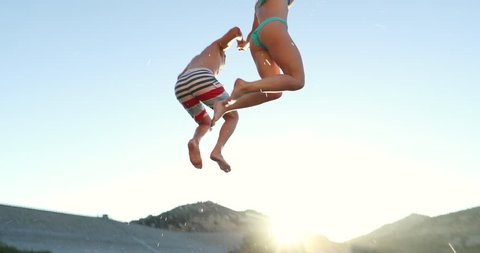 Young Adult Couple Holding Hands Jumping Into Lake In Slow Motion 