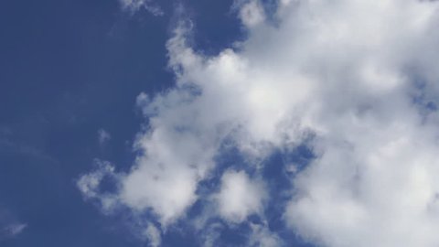 Timelapse of white clouds running over blue sky