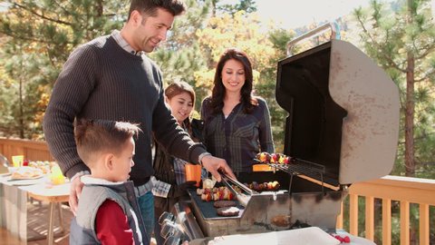 Family barbecuing on a deck in the forest