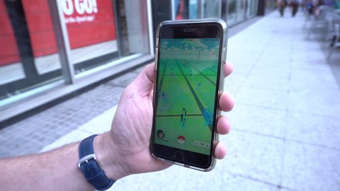 New York City, NY - July 2016: Pokemon Go app being played by a man on his iphone while walking down a manhattan street.  Location based mobile game created by Nintendo uses GPS and camera to interact