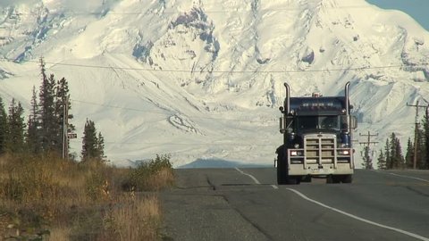 Truck Drives In Front Of Snow Covered Mountain