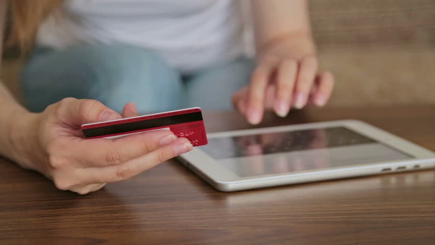 Female buying goods from the internet on her pc tablet with her credit card. Young woman caucasian hands entering number security code from credit card on pad | Shutterstock HD Video #17959936