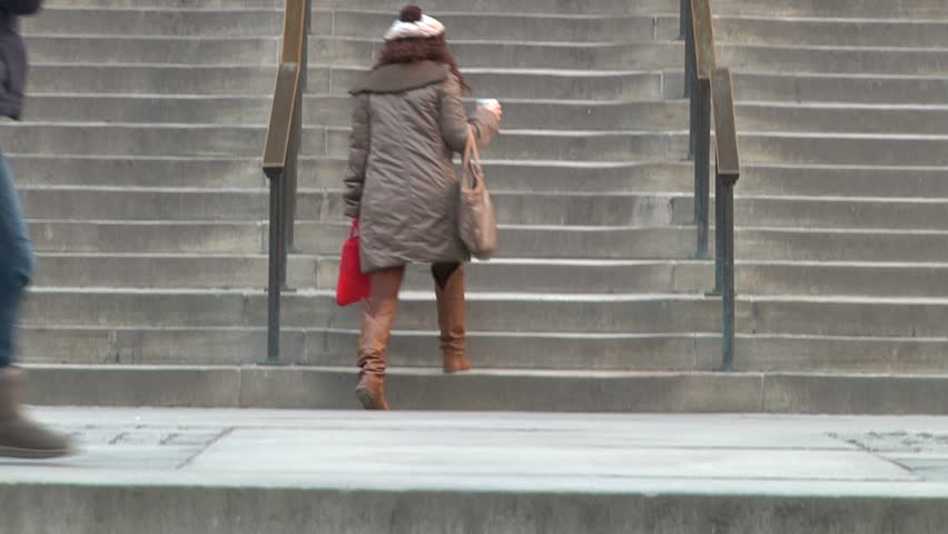 NEW YORK - CIRCA MARCH 2011 - New York Public Library: tilt from people climbing stairs to the facade and revolving door, others leave the building. Pedestrians walk on the sidewalk, girl on cellphone