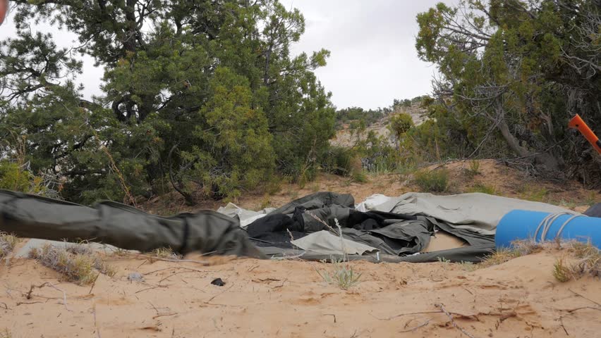 A fast moving time lapse shot of man setting up a tent for camping in the desert mountains. A young toddler or can be seen helping and entering the tent.
