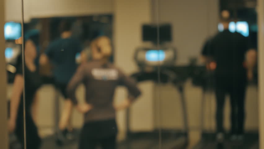The members of the fitness club are training on treadmills, in defocus. Shot in motion
