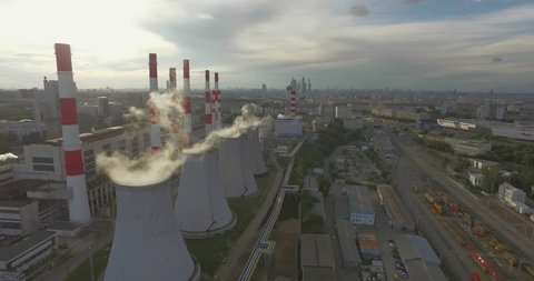 Aerial 4K: Pollution concept, Smoke or Steam from an Industrial Chimney, Thermal Power Plant with Huge Cooling Towers and Steam situated in the Ciity, Industry Scenery, Factory View. 