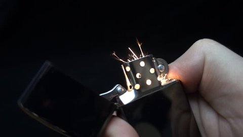 Ignite a zippo in the hand on black background. S-log - High Dynamic Range. Slow motion, high speed camera, 250fps