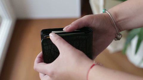 Female hands take out cash dollars from purse, considers cash payday