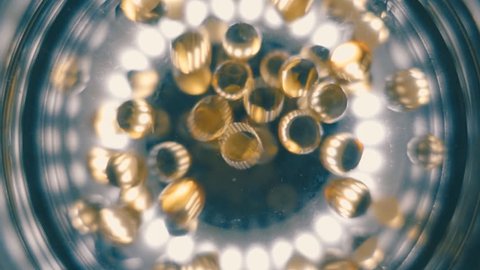 In a glass fall transparent yellow balls, a medicine capsules. Slow motion, high speed camera, 250fps