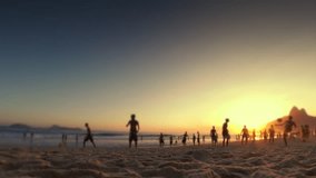 Silhouettes of carioca Brazilians playing altinho beach soccer at sunset on the shore at the Posto Nove section of Ipanema Beach in Rio de Janeiro, Brazil