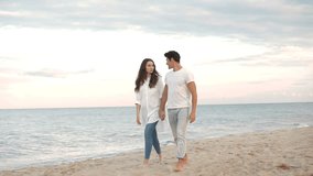 Young romantic beautiful couple walking on the beach and talking