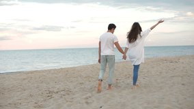 Young romantic couple walking at the beach and holding hands
