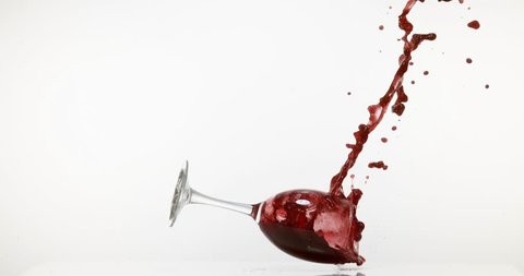 Glass of Red Wine Falling and Splashing against White Background, Slow motion 