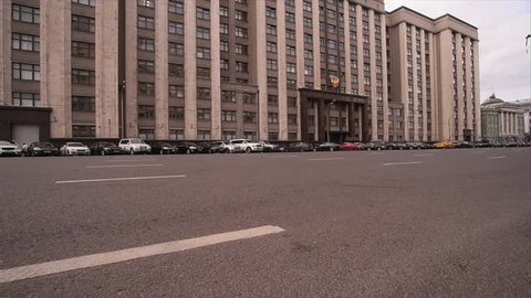 State Duma of the Russian Federation. The building of the state Duma of the Russian Federation with developing the flag, in front of parked cars, Past car ride.