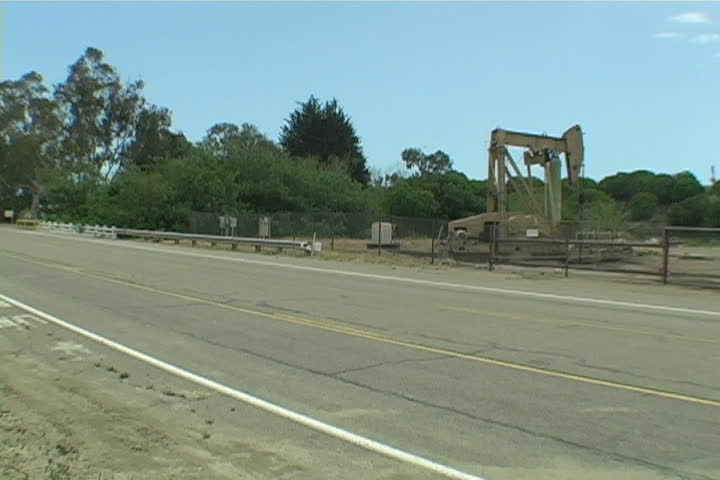 Oil rig pumps oil near an empty road.