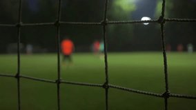 Evening football game slow motion bokeh video. View through mesh