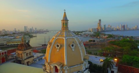 Aerial shot, flying over Cartagena near a domed church background sunset