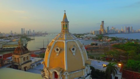 Aerial shot, flying over Cartagena near a domed church background sunset
