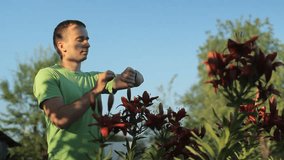 Man touching smart watches around flowerbeds flowers early in the morning