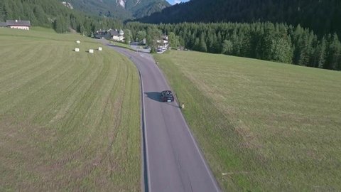Drone aerial flying over a scenic mountain forests and fields in Dolomites, Italy Alps