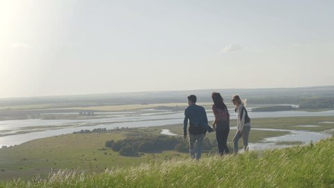 Group Of young happy Friends standing on a high hill at summer evening