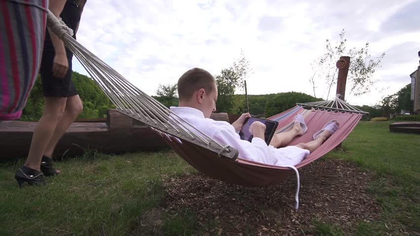 Young Caucasian couple arguing outdoor in the garden. Husband waste time wuth gadgets and wife feels jelaous