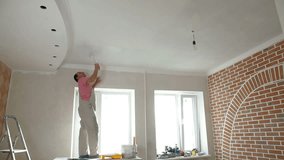 House Painter painting the kitchen ceiling using a paint roller, Wide shot
