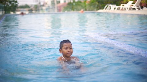Little boy having fun in outdoor swimming pool slowmotion

