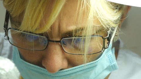 Close up portrait of female doctor in glasses with protective work wear. Female face in medical mask. Cosmetologist or therapist is working