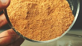 Close-up view of breadcrumbs and spices mixed together pours into a glass bowl in the kitchen.