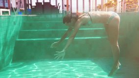 Girl in bikini swimming underwater in blue pool. Cinematic slow motion video.