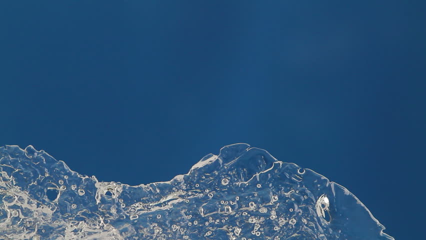 melting ice closeup on blue background. accelerated shoot. reverse