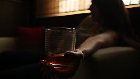 sad lonely woman drinks alcohol in the dark. Glass in sharp focus. female alcoholism