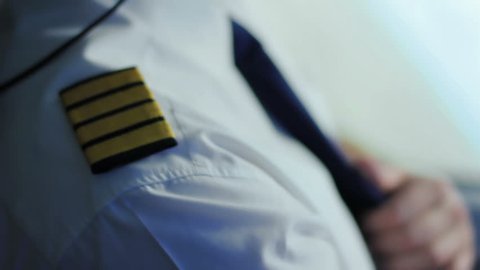 Airline captain sitting in cockpit, adjusting uniform, getting ready takeoff. Aviator in airplane cabin waiting for dispatcher permission, noble profession, confident crew member, commercial flight
