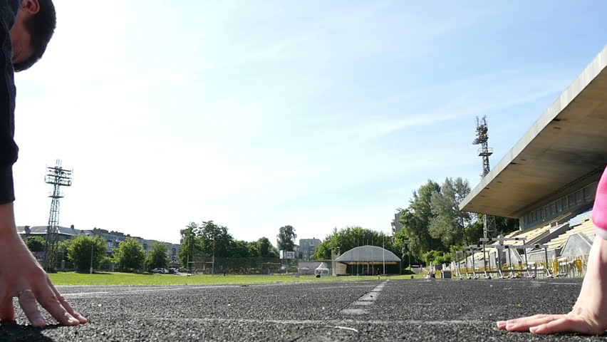 man and woman competing in run at the stadium, slow motion