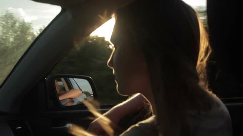 Wind Blowing Through Girl's silhouette and Hair In a car. Sunset