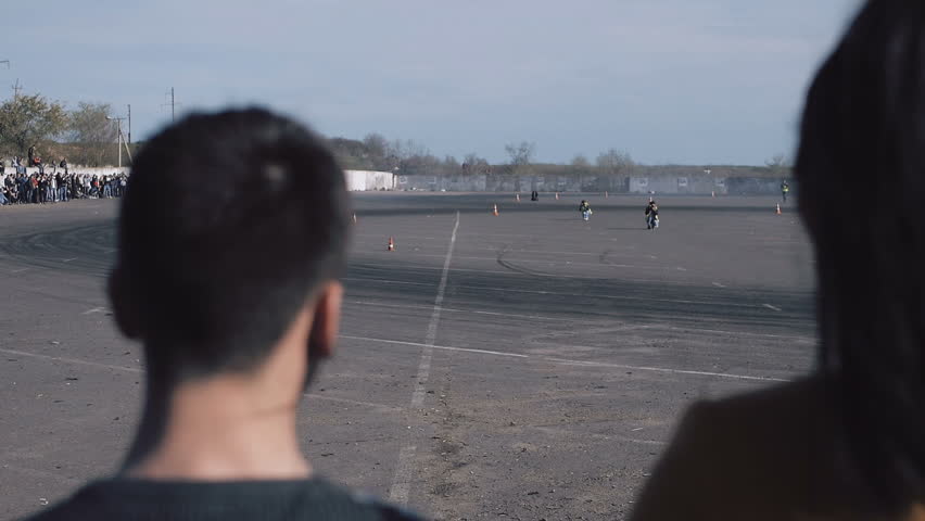 Boys see drifting cars on the race through the crowd at a drift competition