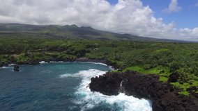 Waianapanapa State Park Black sand beach stationary drone footage with a very wide angle view of enormous crashing waves on the lava rock. 