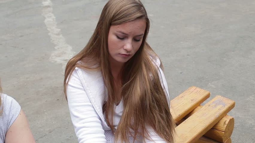 Sad girl sitting on a bench in the street