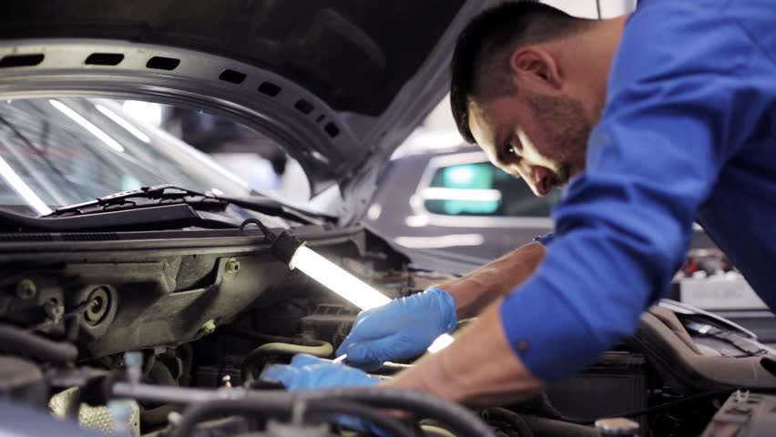 car service, repair, maintenance and people concept - mechanic man with lamp working at workshop Royalty-Free Stock Footage #18085261