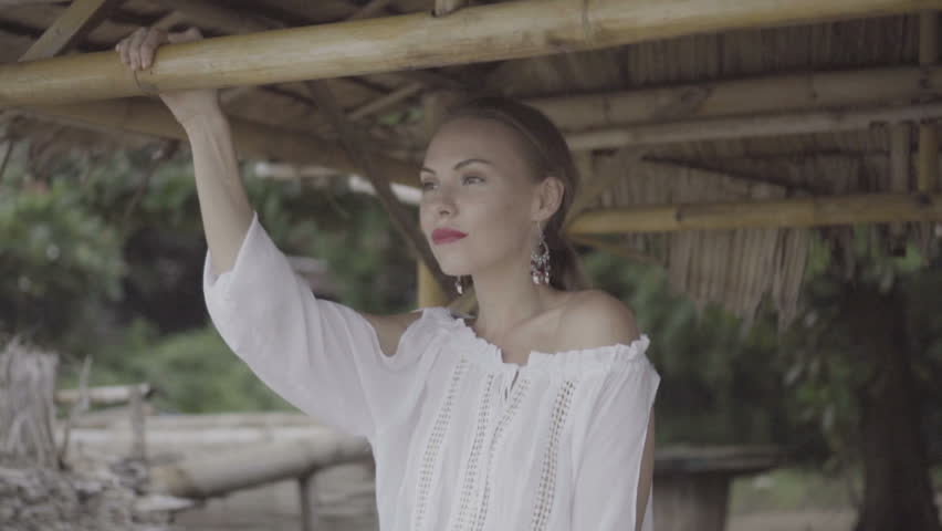 Pretty naturally looking woman in boho style fashion wearing white shirt, hat and earrings on a beautiful summer day - video in slow motion.