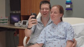 Expecting couple doing video chat on smart phone in hospital. Young couple talking on smartphone with family in medical center before birth of first child.