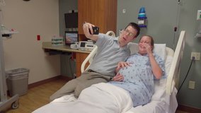 Expecting couple doing video chat on smart phone in hospital. Young couple talking on smartphone with family in medical center before birth of first child.