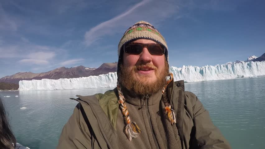Smiling Happy Man With a Beard Shoots Himself and Glacier and the Picturesque Nature Around on a Clear Sunny Day