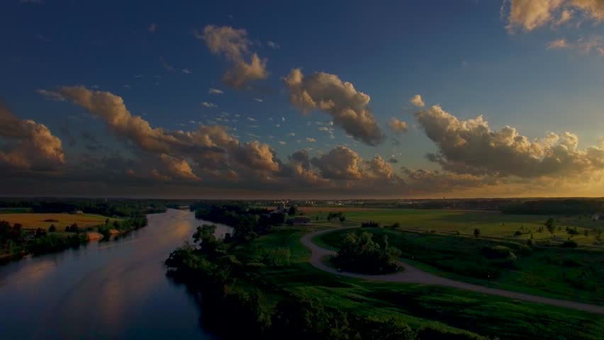 Breathtaking aerial view of sunset with amazing clouds over deep blue river.
