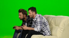 Two guys playing video games with wireless control pad. Green screen