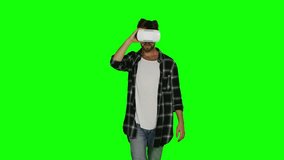 Man in VR mask passes some of virtual obstacles. Green screen